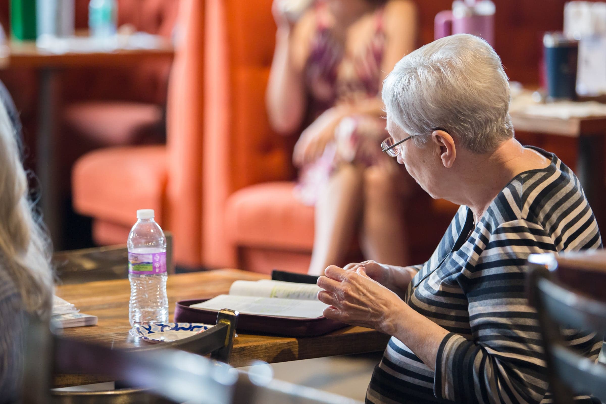 A woman seated at a table with an open Bible